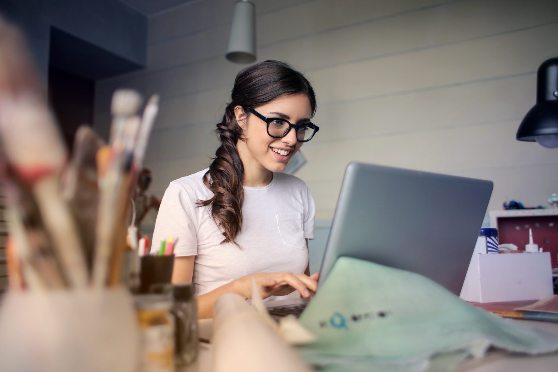 Brown-haired woman smiling as she works on her laptop and build a study protocol on the LifeData web app.